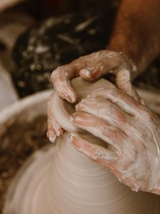 Artisan hands skillfully shaping wet clay on a pottery wheel, focusing on craftsmanship.